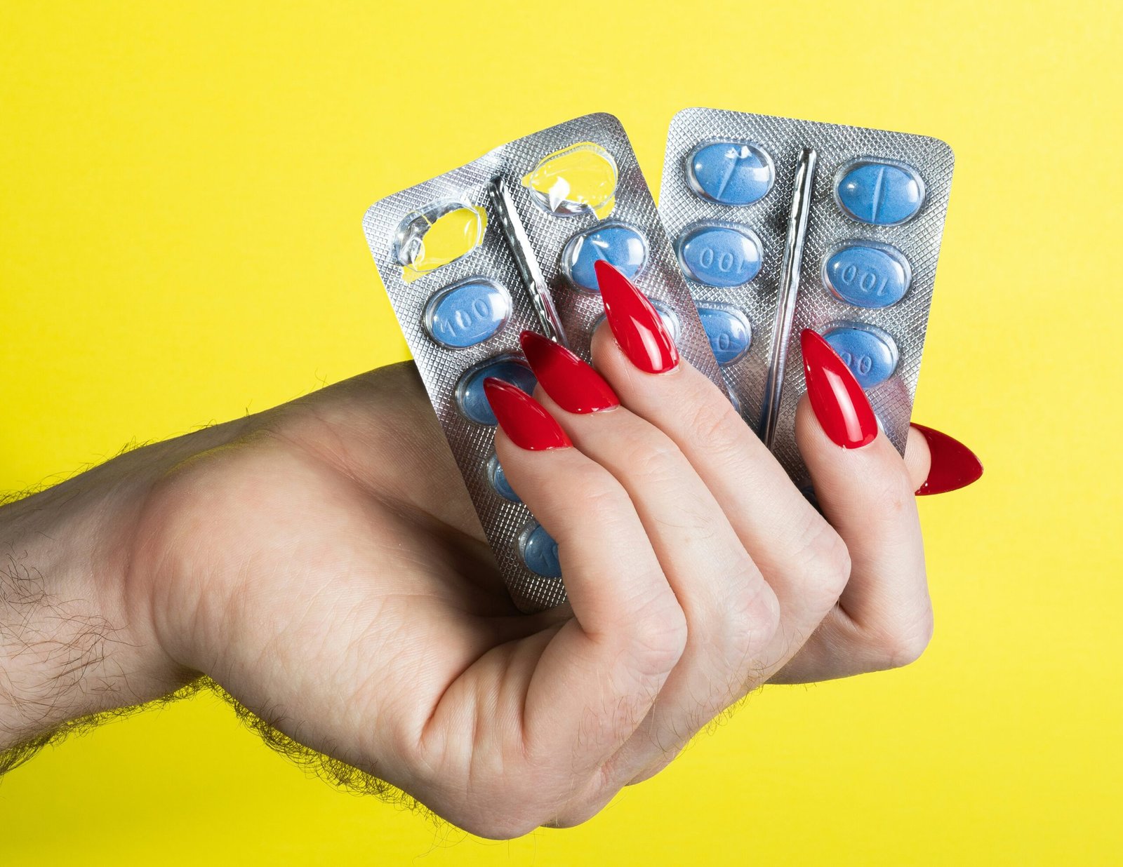 a woman's hand holding two contraptions in front of a yellow background